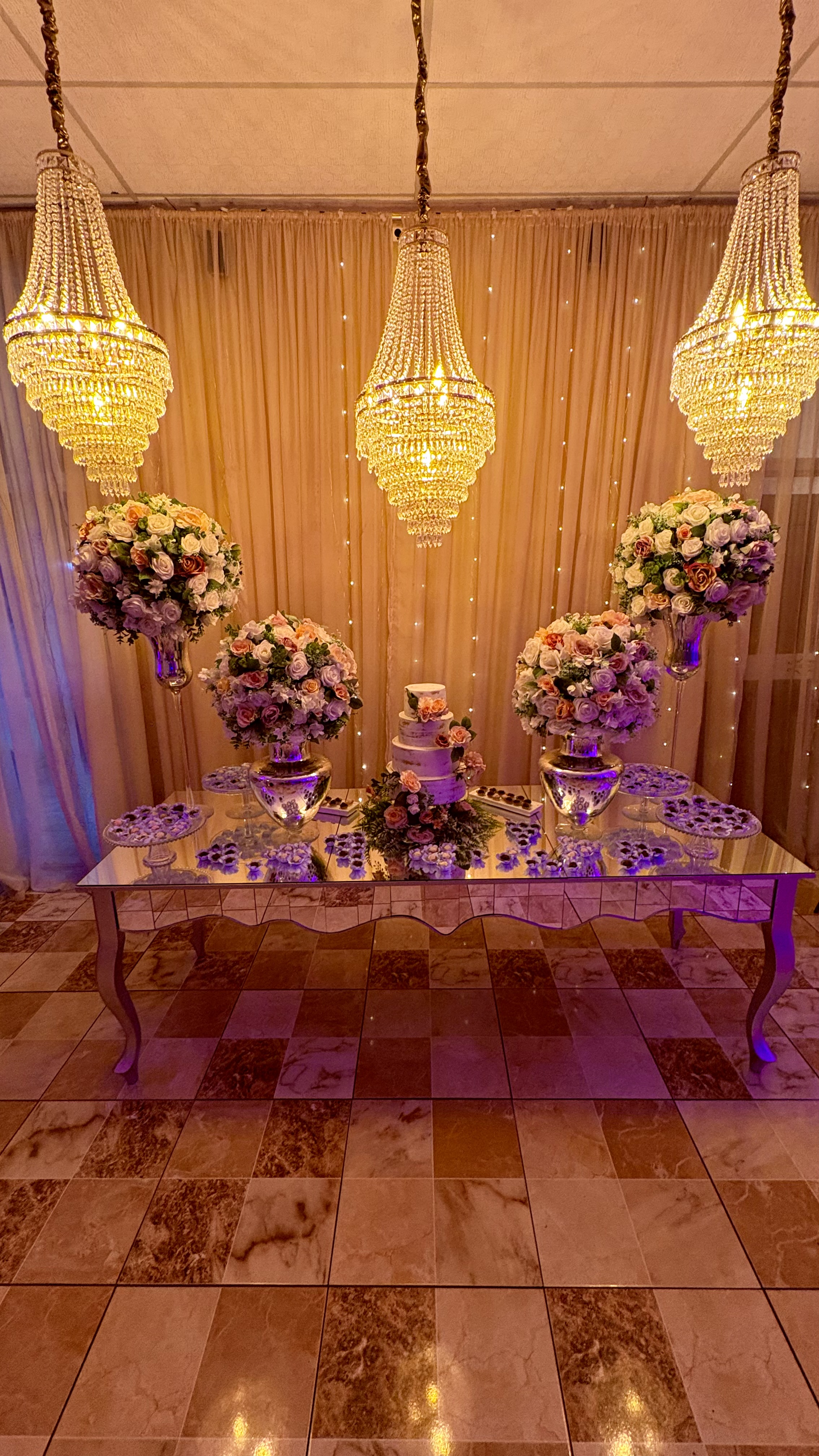 Mesa de doces decorada com flores e lustres